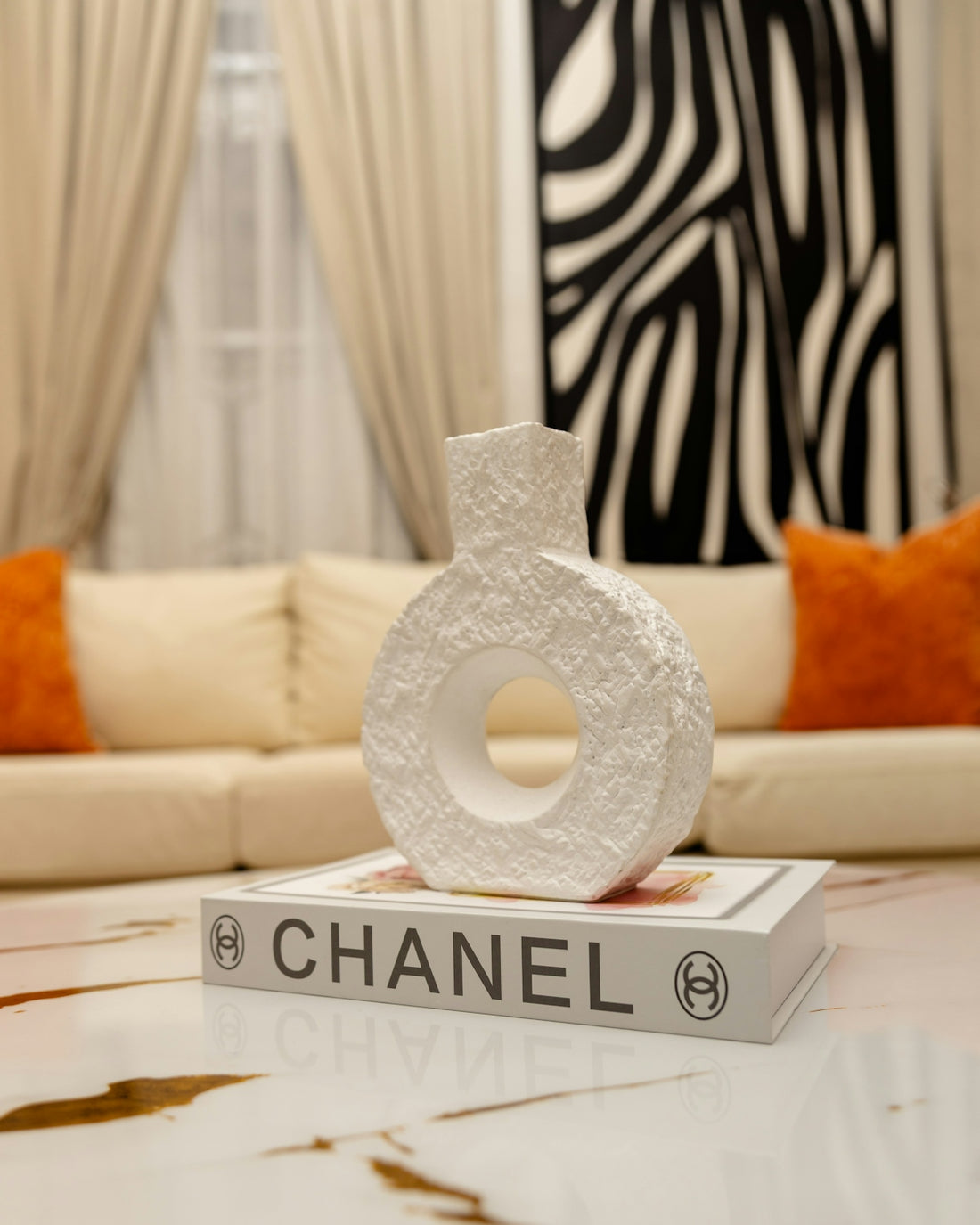 Textured white vase on a chanel book, modern home decor.